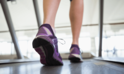 Female Leg and Feet Walking on a Treadmill in Fitness Center Female Leg and Feet Walking on a Treadmill in Fitness Center
