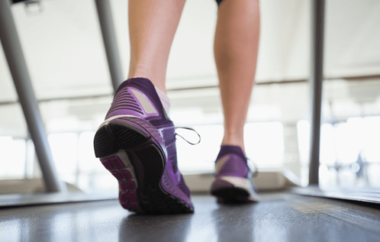Female Leg and Feet Walking on a Treadmill in Fitness Center