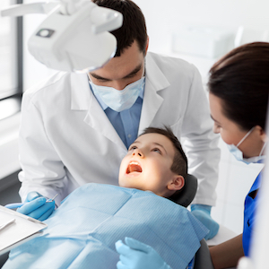 Young Male Getting Teeth Cleaned by 2 Dentists Young Male Getting Teeth Cleaned by 2 Dentists